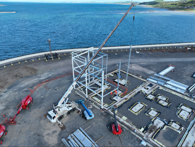 Aerial view of a construction site by the sea, showing a crane.
