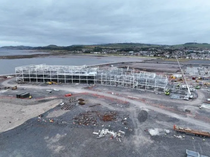 Construction site showing white structures in place, surrounded by the sea.