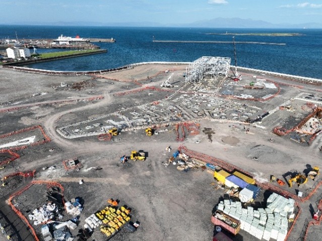 Aerial view of building site containing construction materials looking out onto sea.