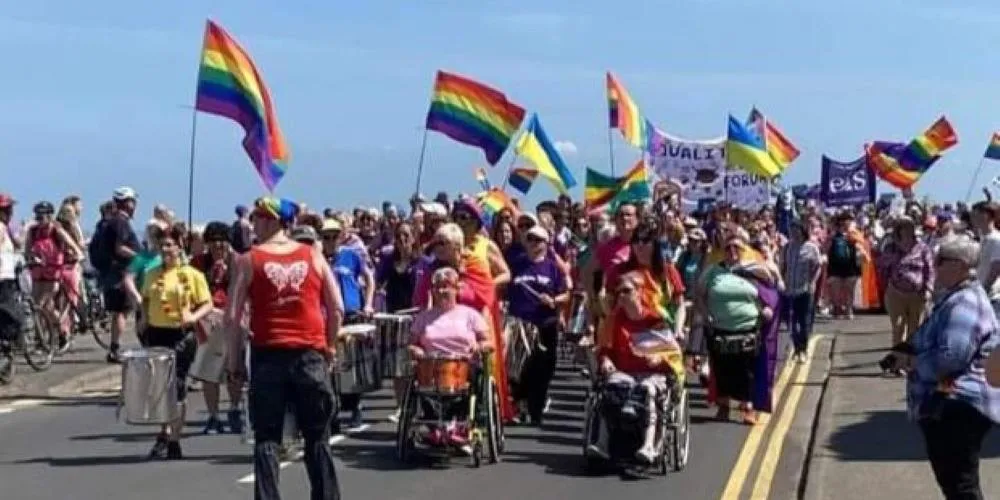 Crowds marching carrying Pride rainbow flags