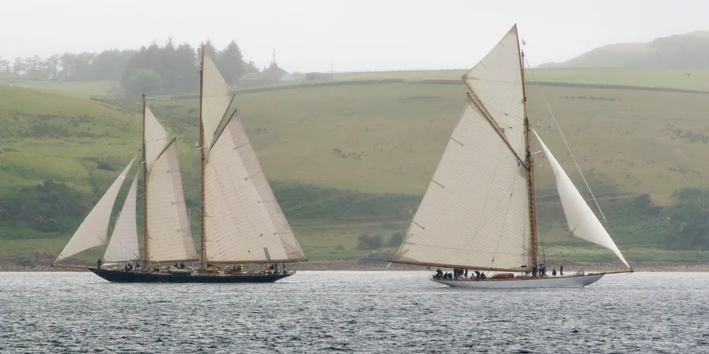 Two Fife Yachts sailing with land in the background