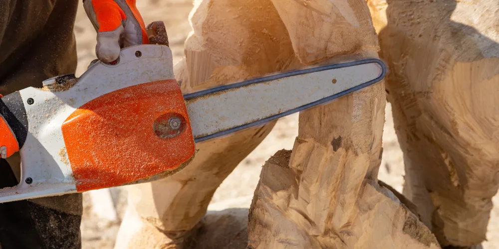 A chainsaw carves a wood sculpture