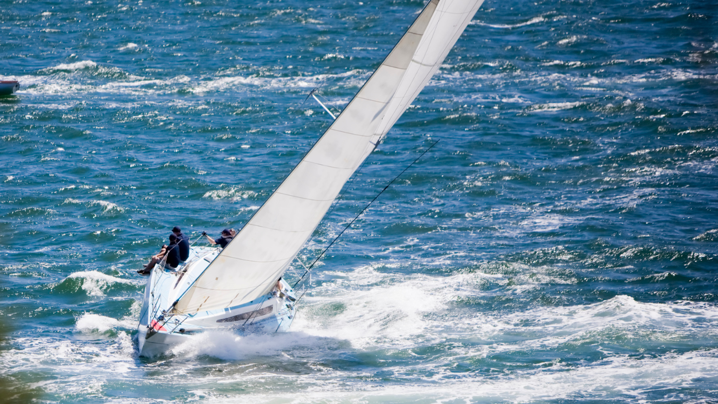 A sailboat riding on sea waves. 