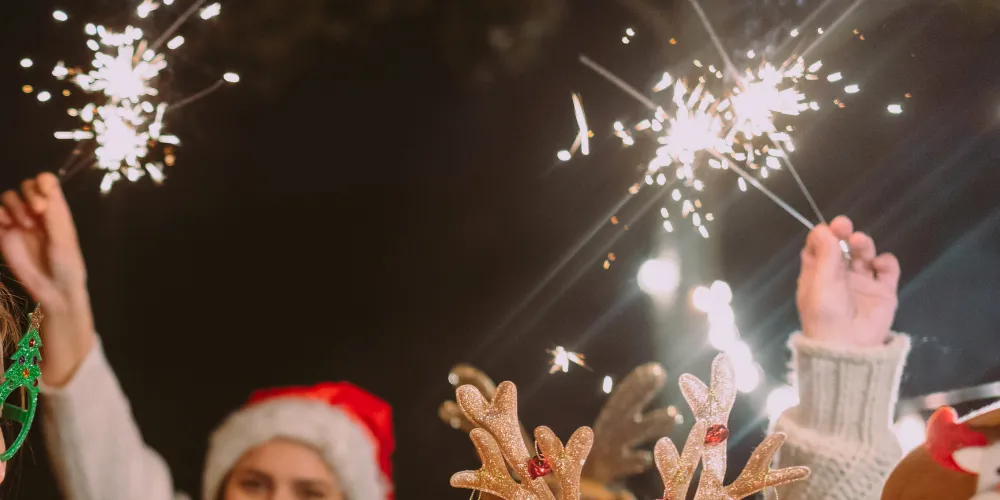 Sparklers in peoples hands with Christmas hats visible