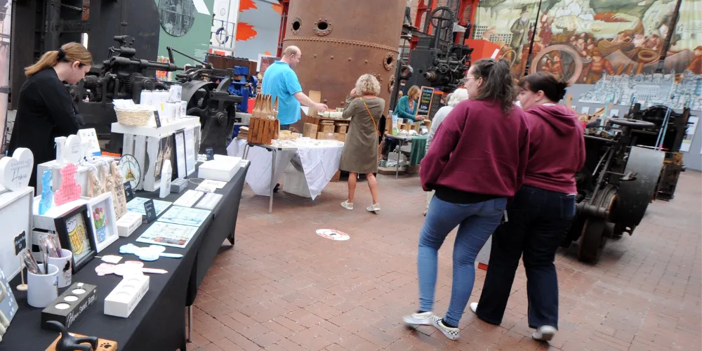 People walking past craft market stalls
