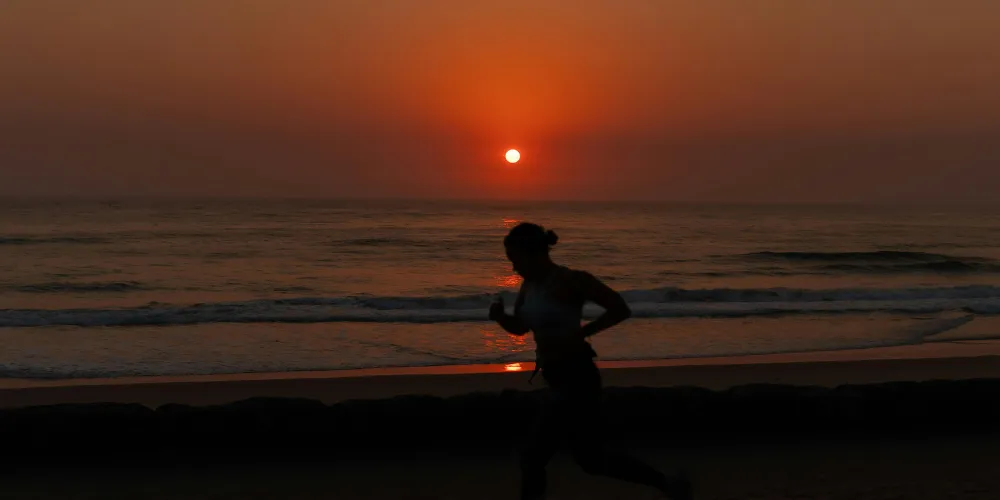 Silhouette of person running on beach at sunset