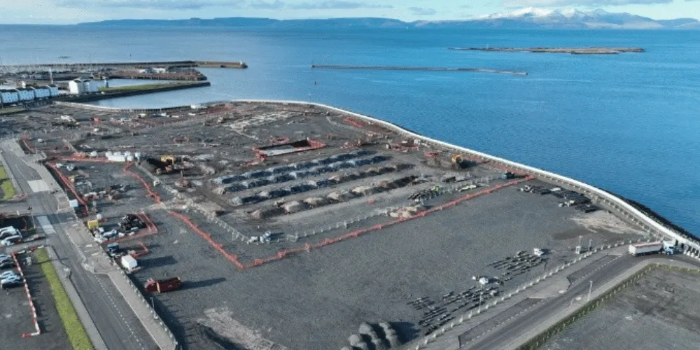 An aerial view of a building site with the sea in the background