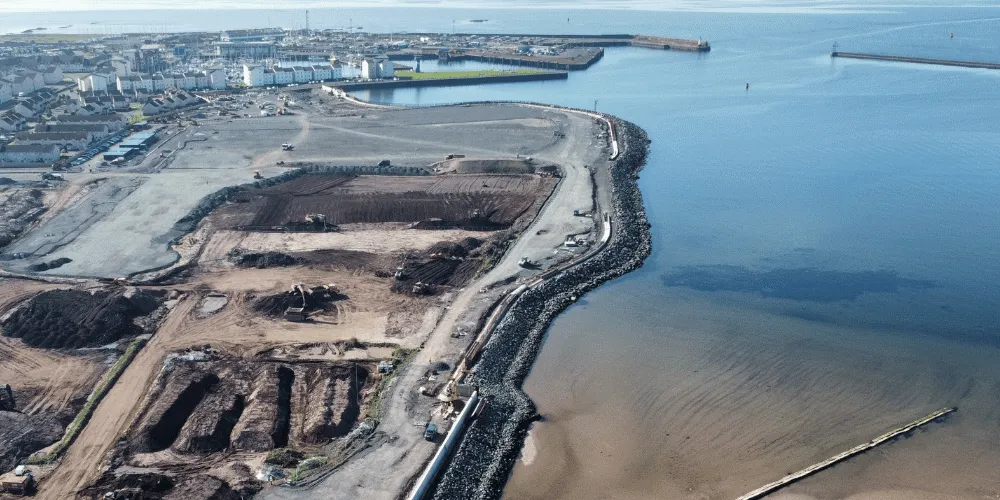 An aeriel view of a construction site with the sea in the background