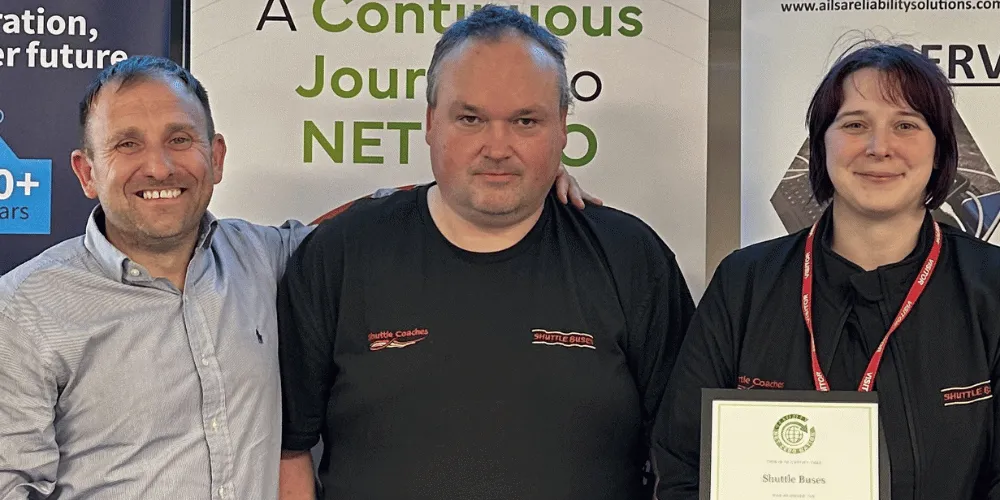 Two men and a woman smiling at the camera. The woman is holding a certificate.