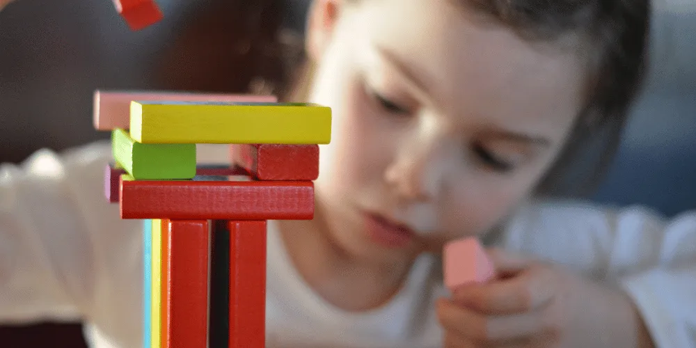 A child playing with colourful wooden building blocks