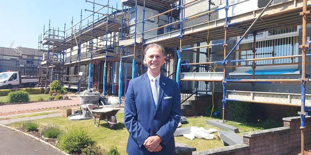 Councillor Tony Gurney standing outside homes with scaffolding up