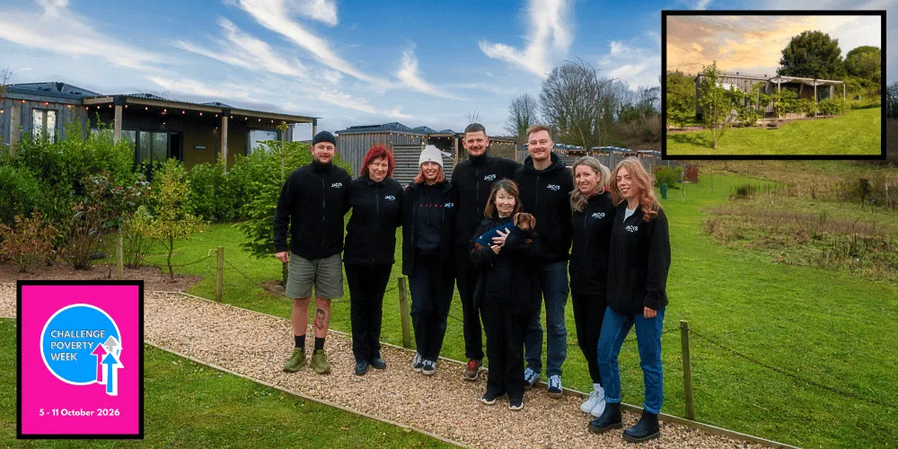 Eight people - one holding a dog, standing in a row with cabin holiday accommodation behind them