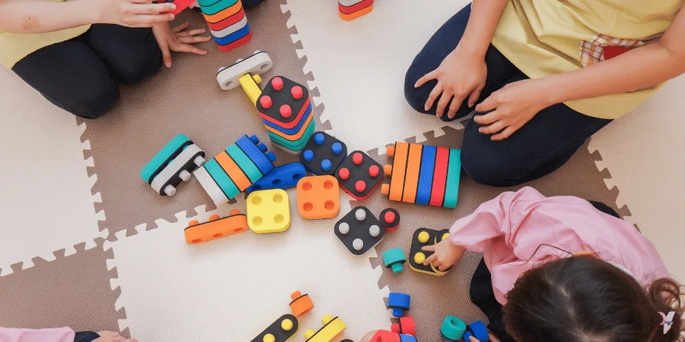 Three young children playing with toys on a mat