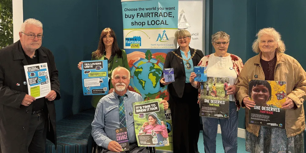 A group of men and women holding Fairtrade Fortnight posters