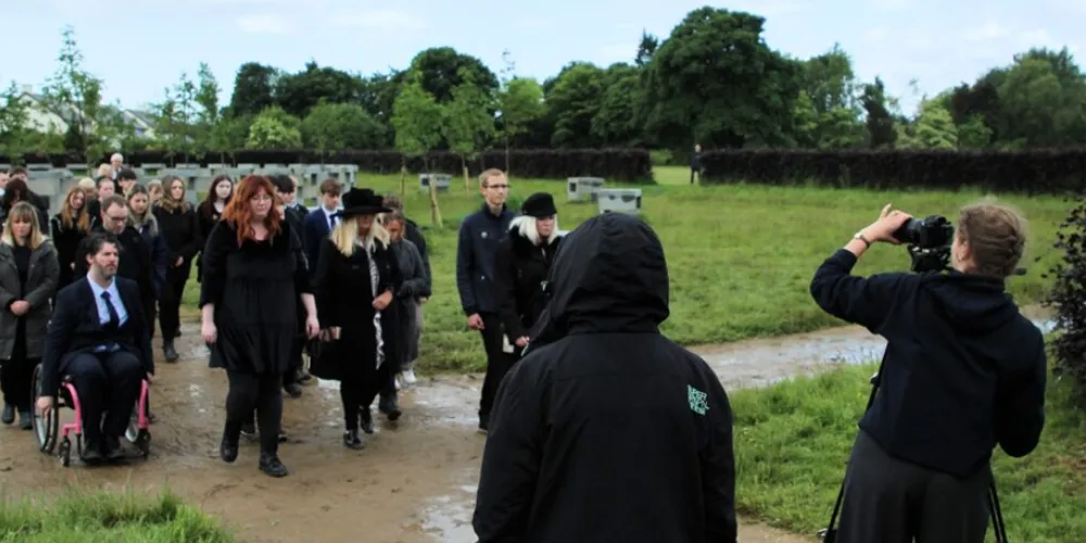 Group of young people in film scene of a funeral at Eglinton Country Park