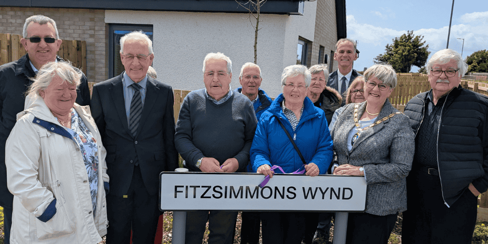 A picture showing a group of about 10 people standing in front of a road sign