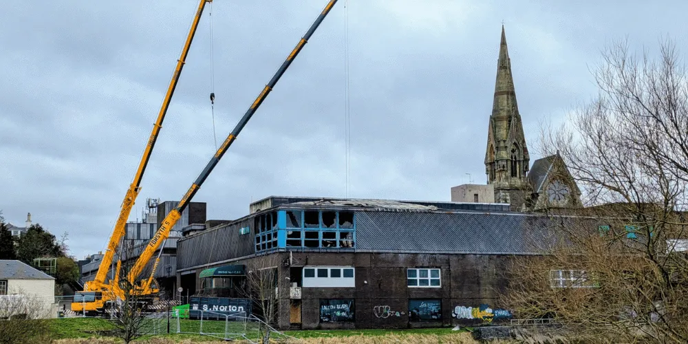 A view of a fire damaged building with cranes adjacent to it