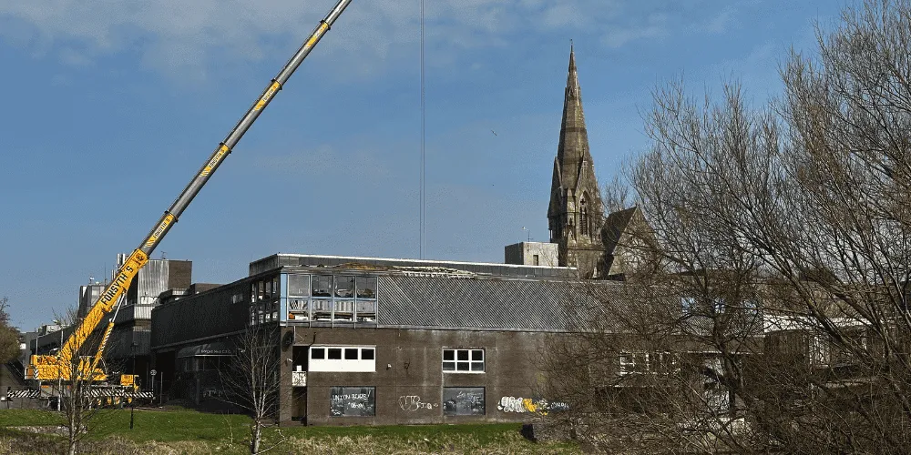 A view of a damaged building with a crane adjacent to it