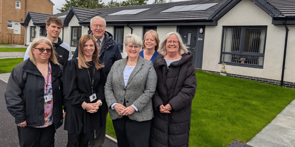 A group of seven people standing in front of newly-built homes