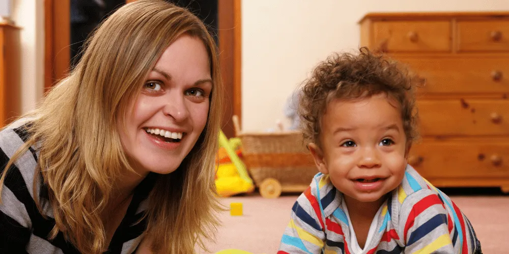 A woman and child playing on the floor with furniture in the background