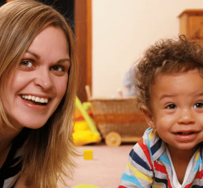 A woman and child smiling with toys in the background