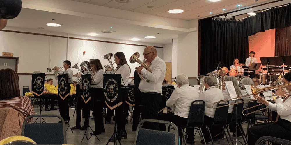 a brass band with approximately 20 members, playing in front of a group of people