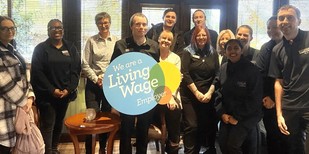A group of staff at Auchrannie Resort holding a Living Wage sign