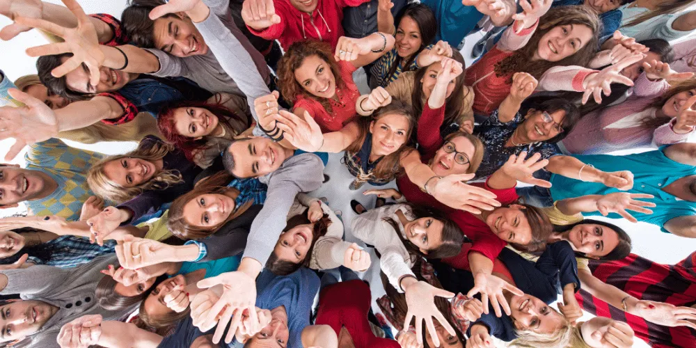 A group of people standing, clustered together, with their arms in the air and looking upwards