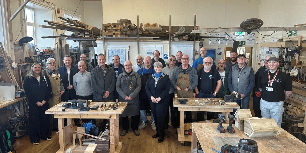 Group photo showing Men's Shed members and councillors in their workshop