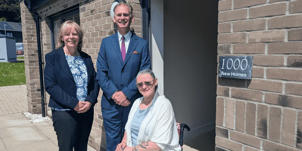 Three people, smiling in front of a newly built house