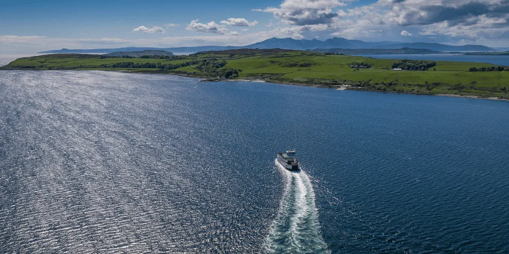 A small boat on the water travelling along the Largs coastline on a sunny day