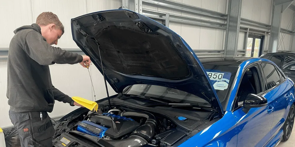 Young man working on repairing a blue car