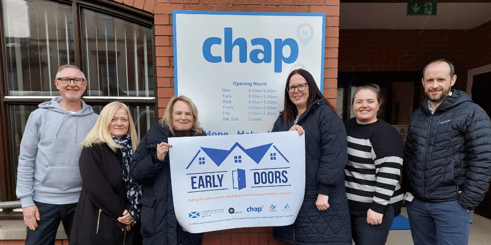 FOUR WOMEN AND TWO MEN, HOLDING A BANNER, FACING THE CAMERA