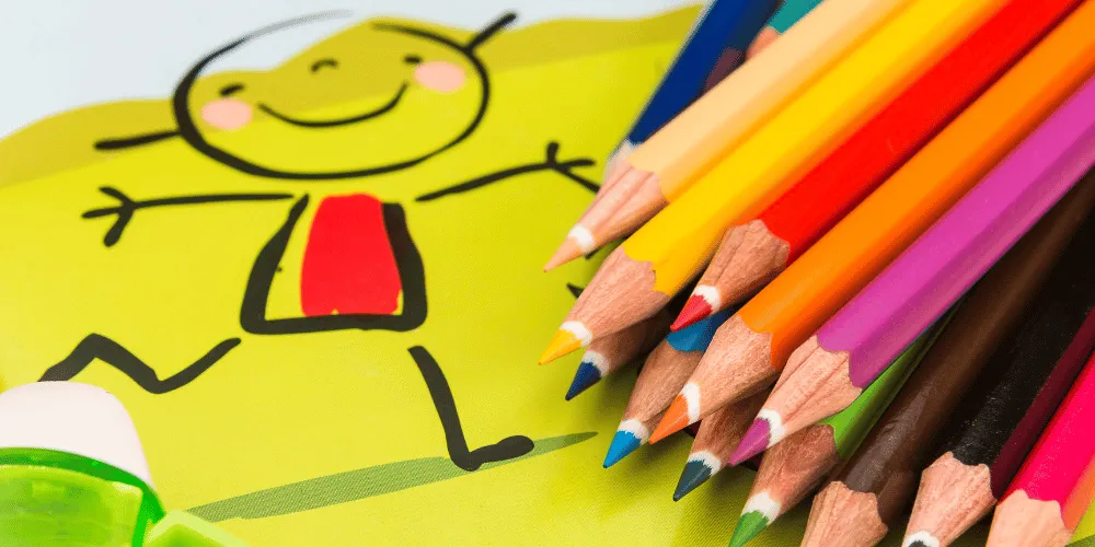 A collection of coloured pencils on top of a drawing of a young child