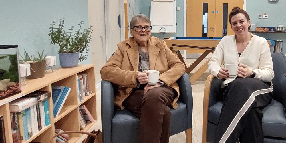 Two women sitting down drinking a coffee
