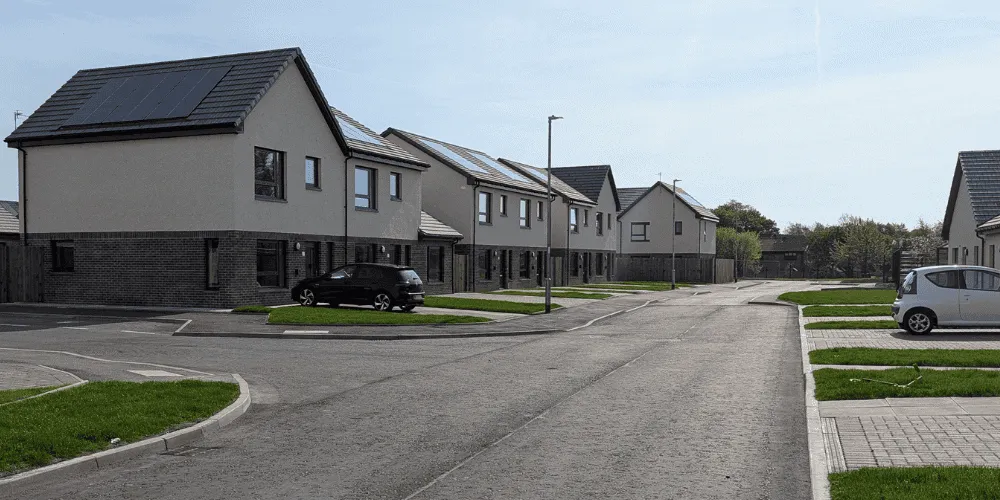 A general view of a street with a number of houses and a clear blue sky
