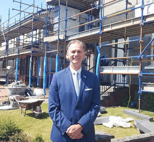 Councillor Tony Gurney standing near homes with scaffolding