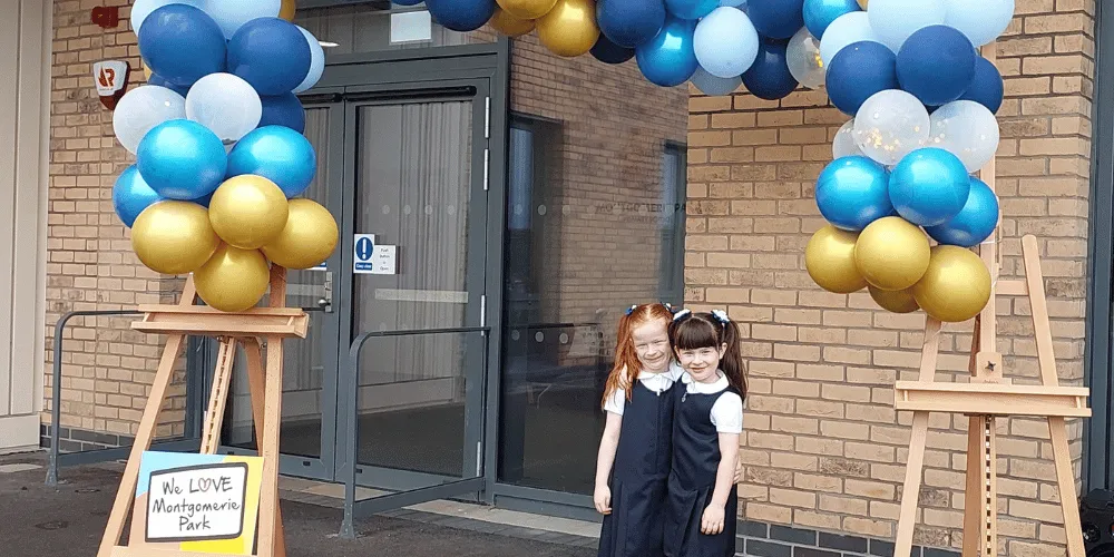 Two girls standing under a balloon arch