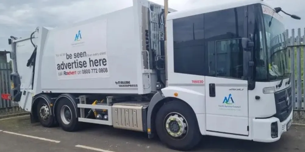 A refuse vehicle with advertising logo on the side
