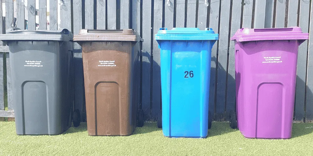 Four coloured waste bins in a row