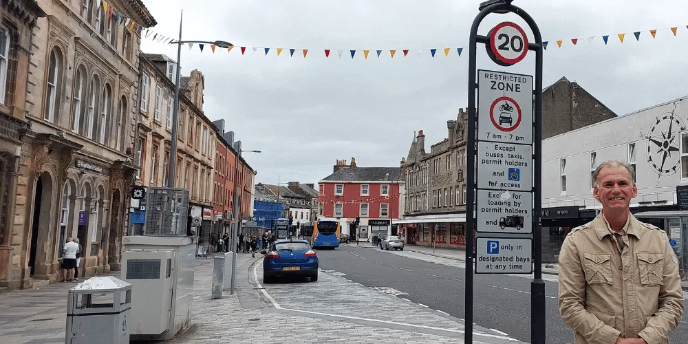 Councillor Tony Gurney standing on a street next to a 20mph road sign